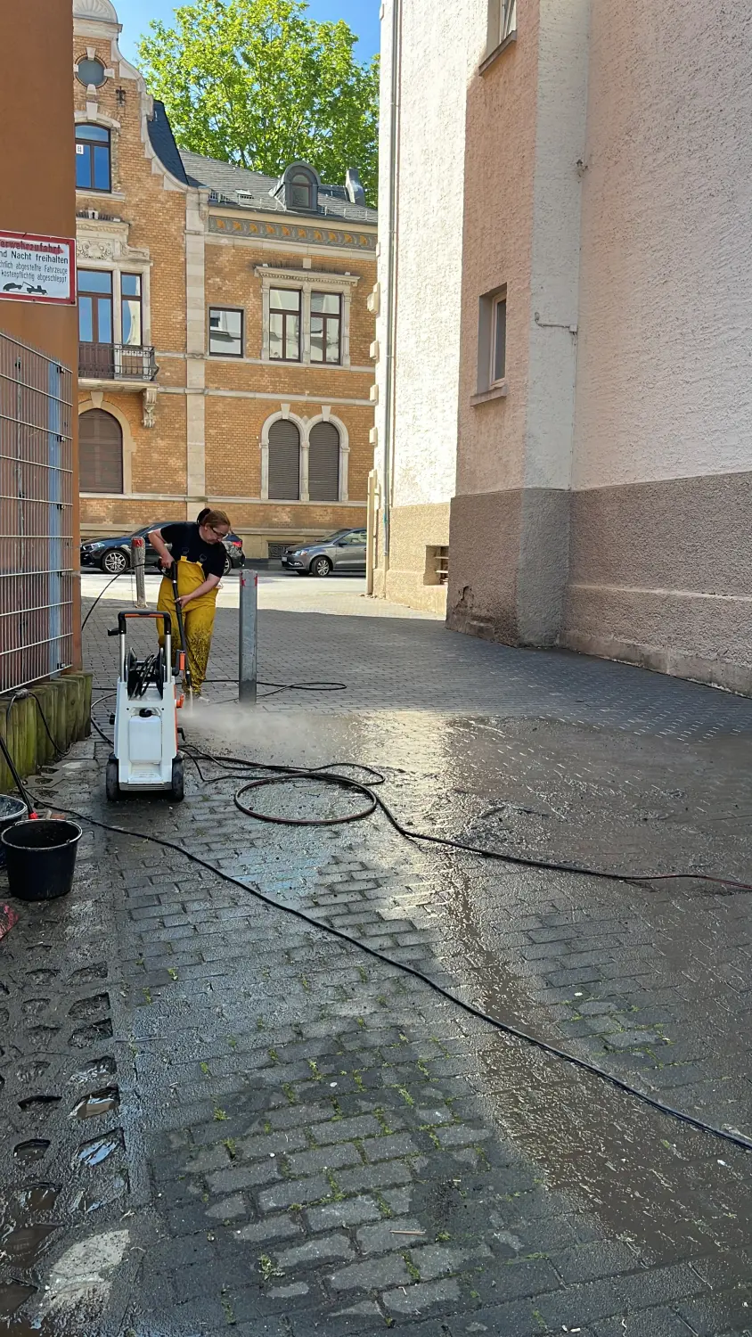 Kamer Dienstleistungen - eine Arbeiterin reinigt den Maurerboden mit Wasserdruck
